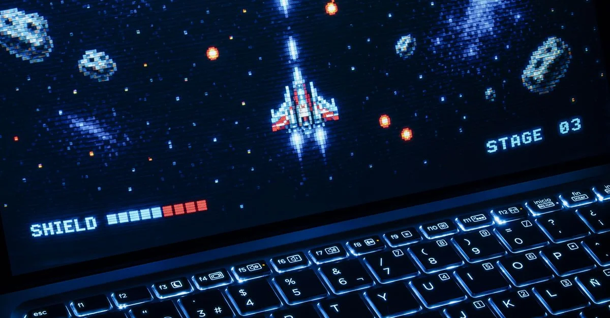Un jeu d'arcade classique de tir spatial affiché sur un ordinateur portable avec un clavier éclairé, montrant des graphismes rétro.
