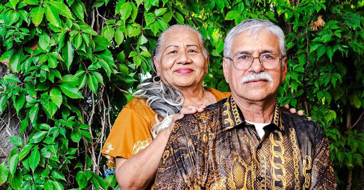 Couple senior se tenant ensemble à l'extérieur dans des vêtements vibrants avec un arrière-plan de feuillage vert luxuriant.