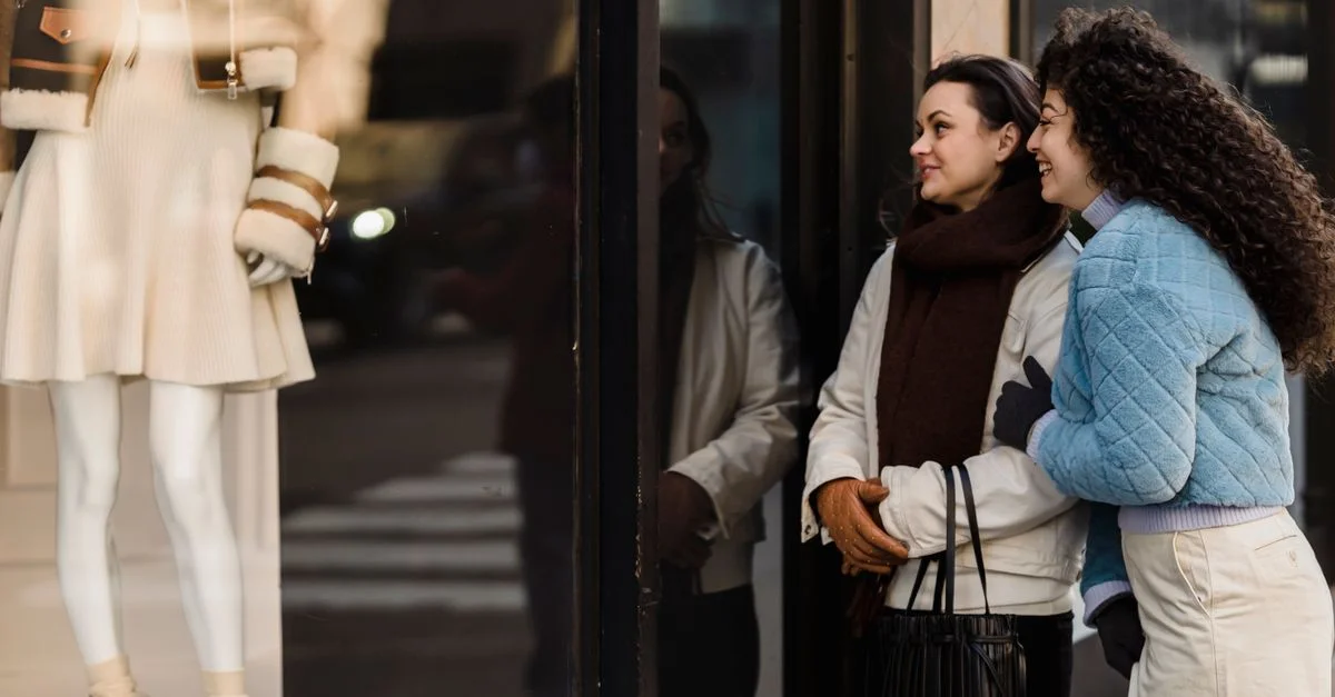 Deux femmes profitant du lèche-vitrine dans un quartier urbain chic, reflétant la joie et l'amitié.