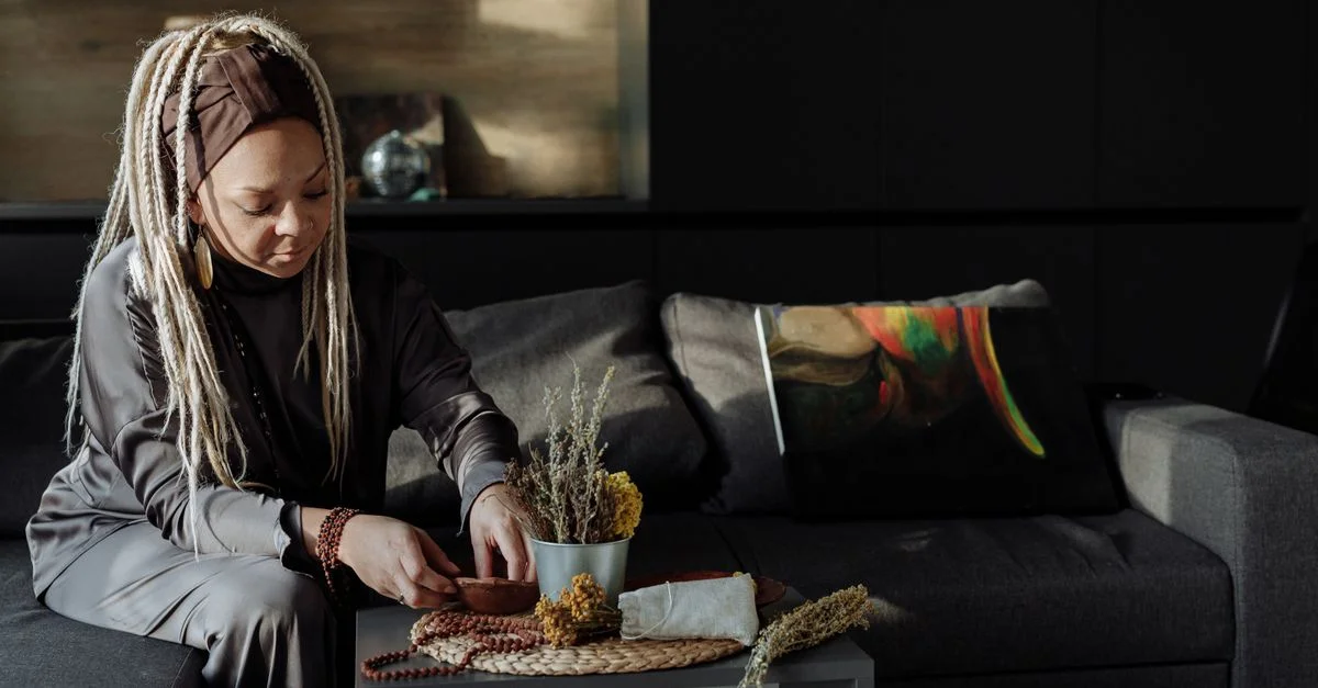 Femme paisible avec des dreadlocks méditant à l'intérieur avec de la lumière naturelle.