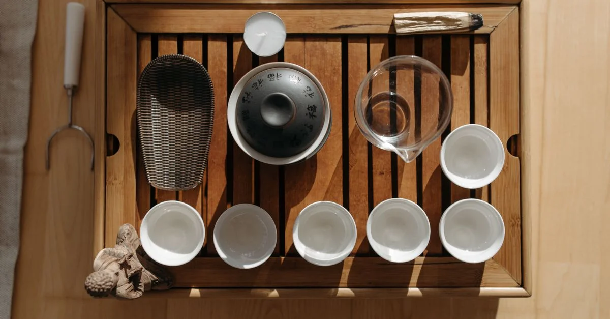 Vue de dessus d'un plateau en bois préparé pour une cérémonie du thé traditionnelle, avec des tasses à thé et des accessoires.